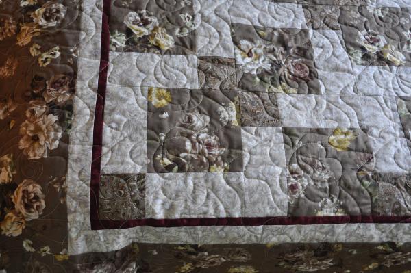 Close up of the pattern and borders of a Disappearing 9 Patch quilt pattern in brown paisley and rose fabrics, with a touch of burgundy.