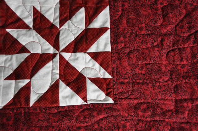A shot of a corner to the quilt top overlaid against the backing fabric.