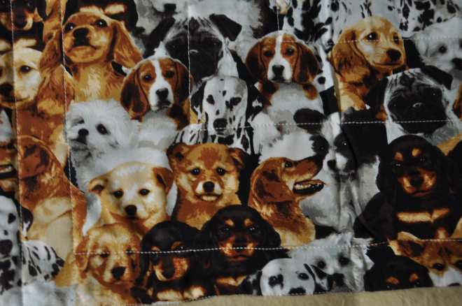 A close-up of some of the puppy mugs on the front of the blanket.