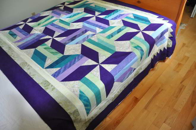 A shot from the side of the quilt on the bed shortside going top to bottom.